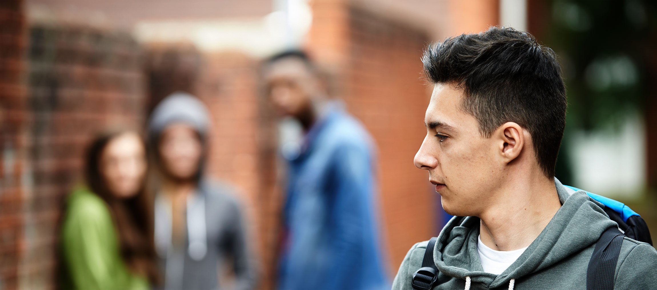 A young man peers over his shoulder at some other teenagers.